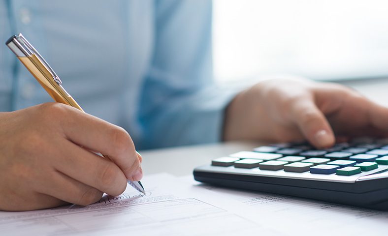 Como contabilizar a venda do ativo imobilizado - pessoa fazendo o cálculo com calculadora, caneta e papel