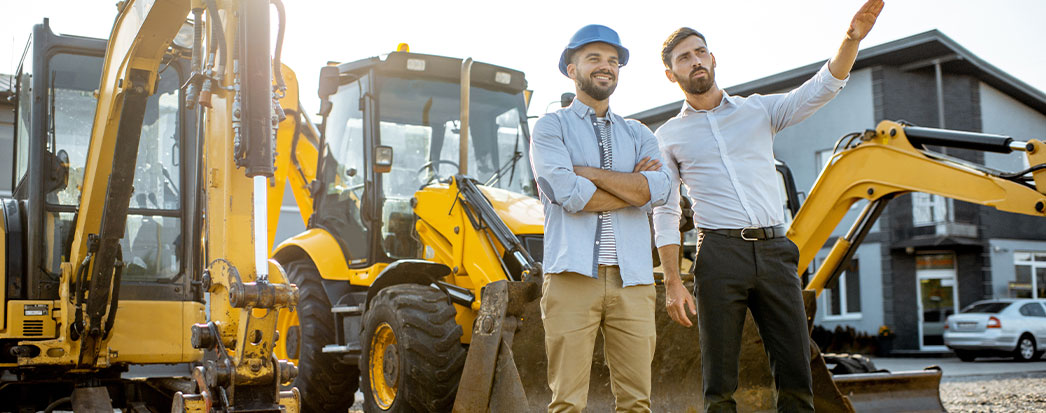 dois homens a frente, máquinas em obras ao fundo, exemplo de ativo não circulante