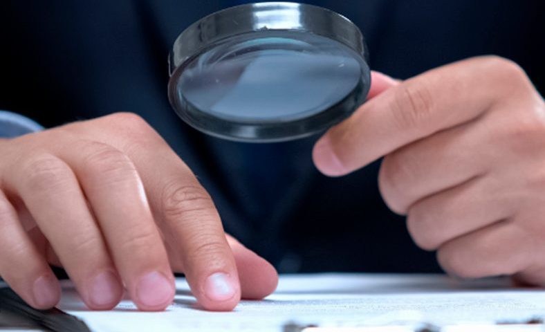 Pessoa lendo um documento em uma lupa