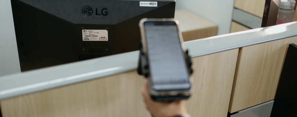 maos segurando leitor e apontando para etiqueta rfid para colher informações durante o inventário